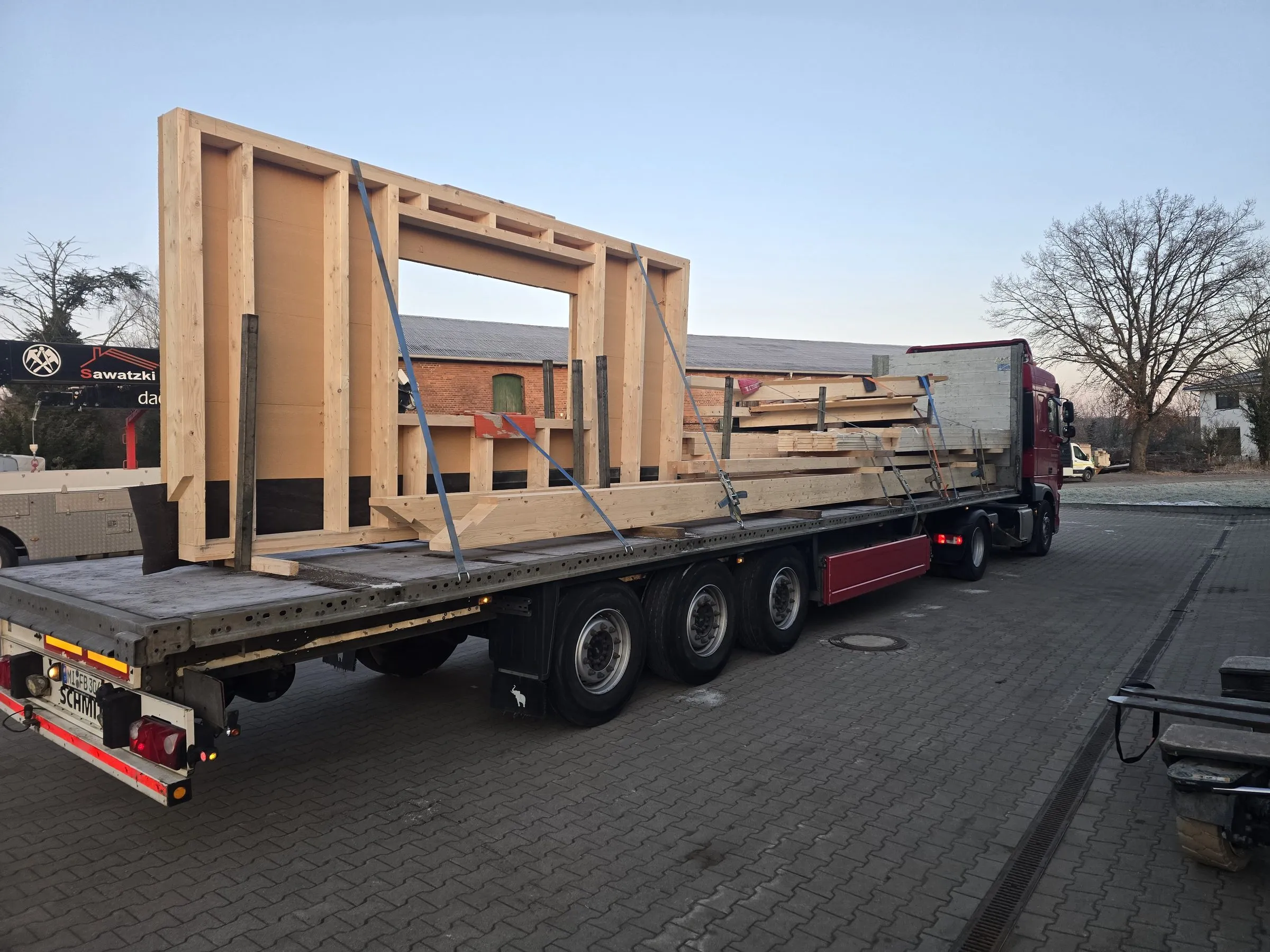 Vorgefertigte Bauteile verladen auf dem Tieflader vor der Halle